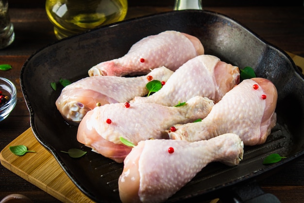 Pés de galinha crus em uma frigideira em uma tabela de madeira. Ingredientes da carne para cozinhar.