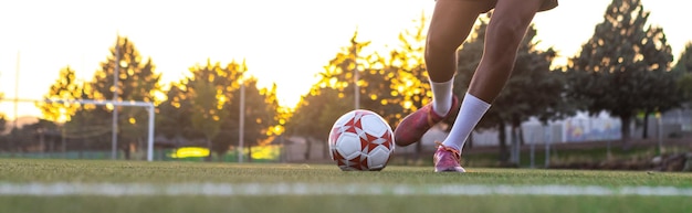 Pés de jogador com a bola marcando um gol Jogador de futebol no campo correndo com a bola Pés de jogador de futebol correndo com a bola na frente do campo de gol