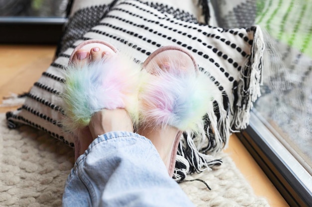 Pés de mulher com pedicure rosa em chinelos coloridos de arco-íris