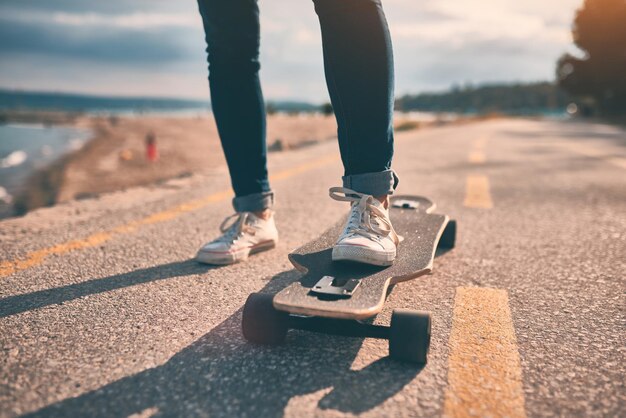 Pés de mulher de tênis em um longboard à noite