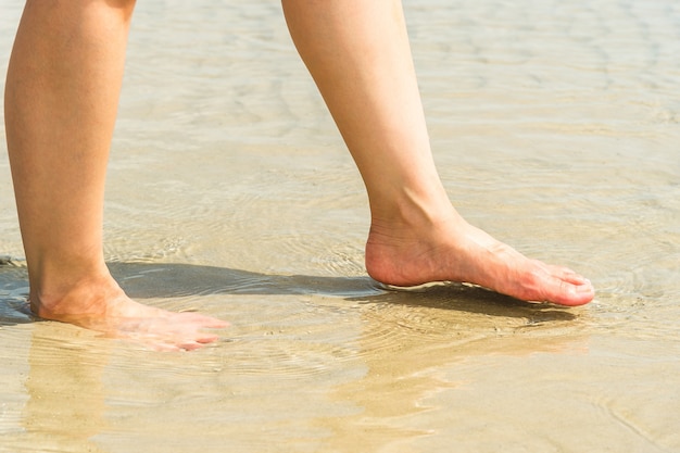 pés de mulher na água na praia