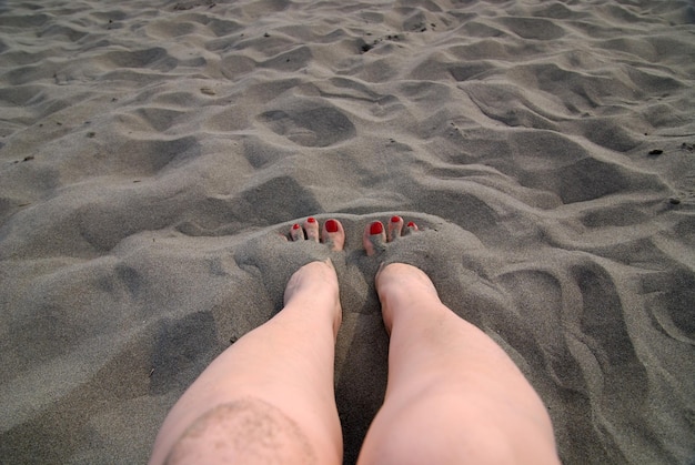 pés de mulher na areia da praia