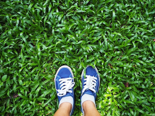 Foto pés de mulher selfie usando tênis azul na grama verde