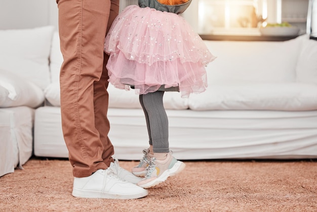 Pés de pai e filho dançando na sala de estar de sua casa de família moderna ao som de música ou rádio Energia de dança e close-up de um homem se divertindo e de pé com sua filha em sua casa