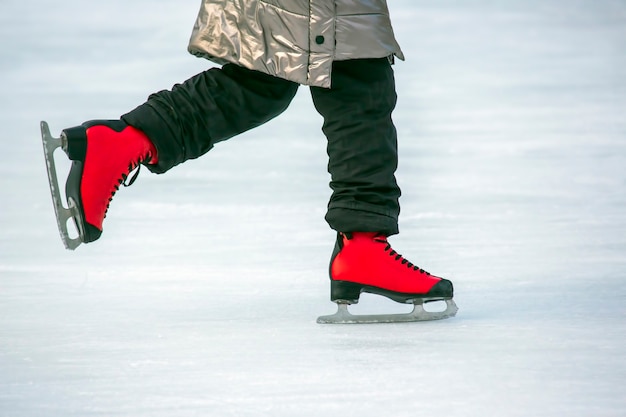 Pés de patins vermelhos em uma pista de gelo. Hobbies e esportes. Férias e atividades de inverno.