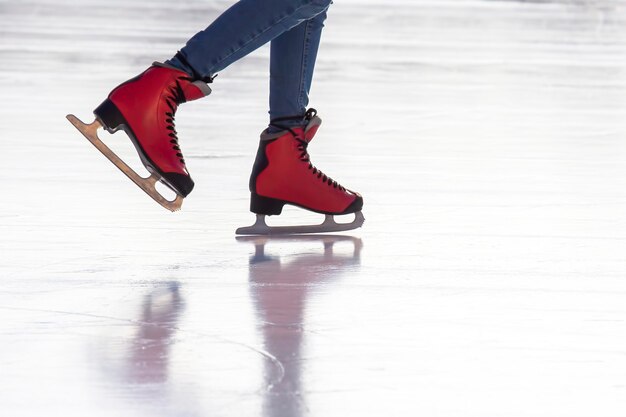 Foto pés de patins vermelhos em uma pista de gelo. hobbies e esportes. férias e atividades de inverno.