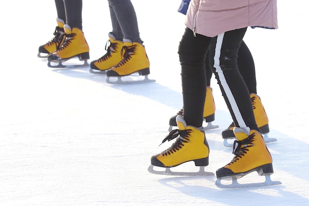 Pés de pessoas patinando em uma pista de gelo de rua. esporte e entretenimento. descanso e férias de inverno.