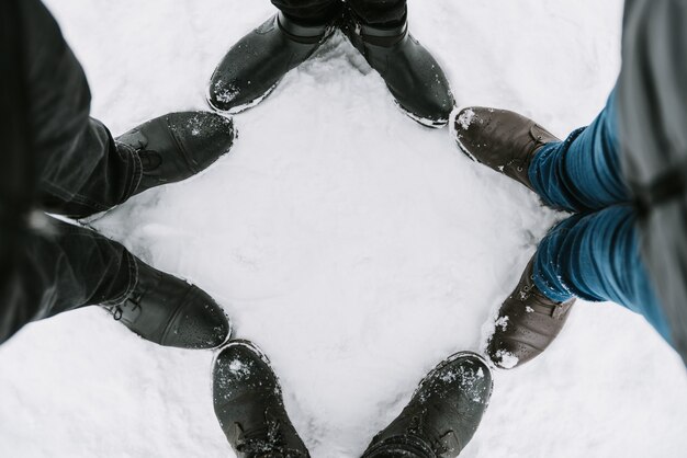 Pés de quatro pessoas na neve, close-up