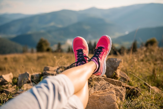 Pés de uma garota esportiva relaxando na paisagem de montanhas