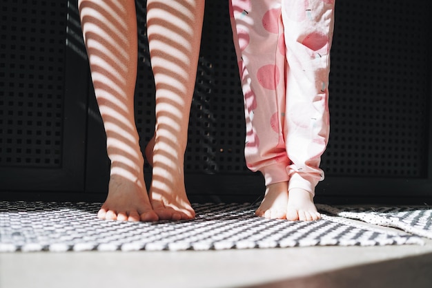 Foto pés descalços de mãe e filha no banheiro em casa luz e sombra