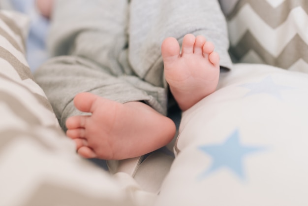 Pés descalços de um bebê recém-nascido em uma calça cinza