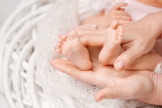 Pés do bebê nas mãos da mãe. pés do bebê recém-nascido minúsculo na fêmea em forma de mãos closeup. mãe e seu filho. conceito de família feliz. linda imagem conceitual da maternidade