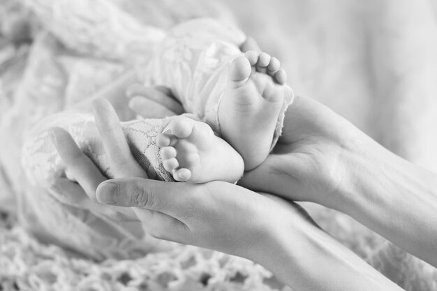 Pés do bebê nas mãos da mãe Pés do bebê recém-nascido minúsculo nas mãos em forma feminina closeup Mãe e seu filho Conceito de família feliz Linda imagem conceitual da maternidade