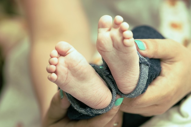 Pés do bebê recém-nascido nas mãos da mãe