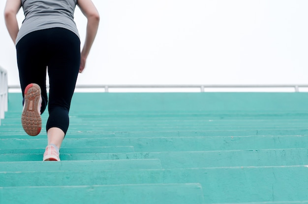 Pés do corredor da mulher que exercitam a correr na escada na ginástica, está movimentando-se