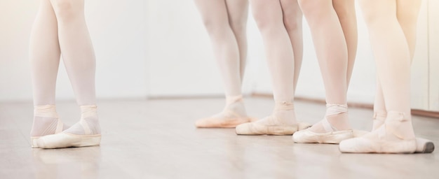 Pés do líder de balé e do grupo de dançarinos no treinamento de estúdio de dança na academia de artistas com parede branca e piso Aula de equipe feminina ou alunos dançando em sapatilhas para desempenho escolar com reflexo de lente