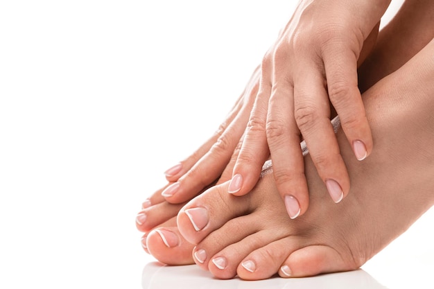 Pés e mãos femininos com manicure francesa de pele macia e pedicure em fundo branco