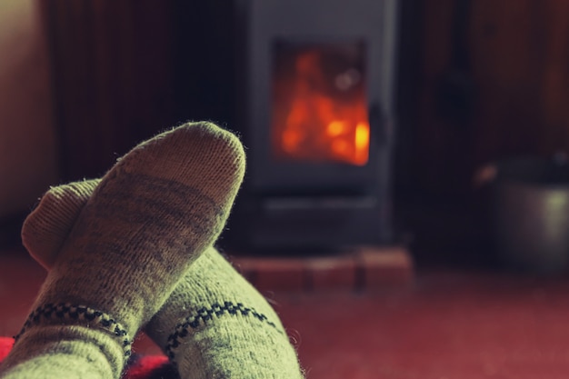 Pés em meias de lã de inverno na lareira