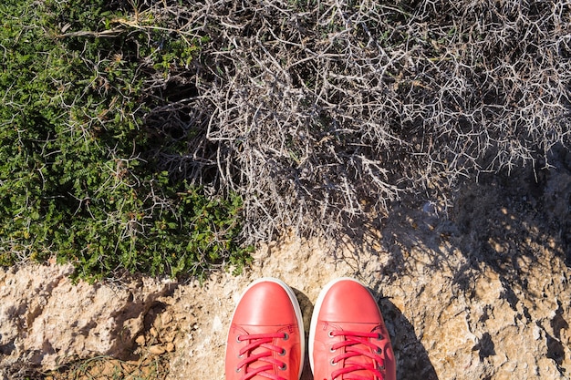 Pés em sapatos casuais rosa no fundo de pedra.