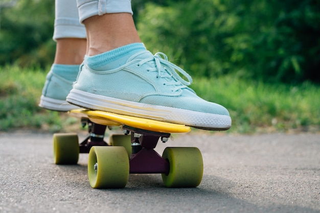 Pés femininos de tênis em um close do skate amarelo