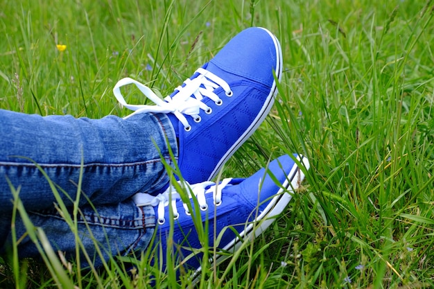 Pés femininos em sapatos desportivos no fundo da grama verde