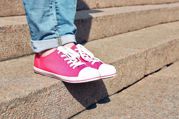 Pés femininos em sapatos rosa em escadas de pedra