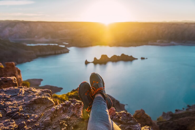 Foto pés femininos na montanha. mulher feliz apreciando a vista do lago ao pôr do sol