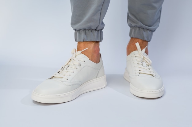 Pés masculinos em tênis branco do dia a dia feitos de couro natural com cordão. Foto de alta qualidade