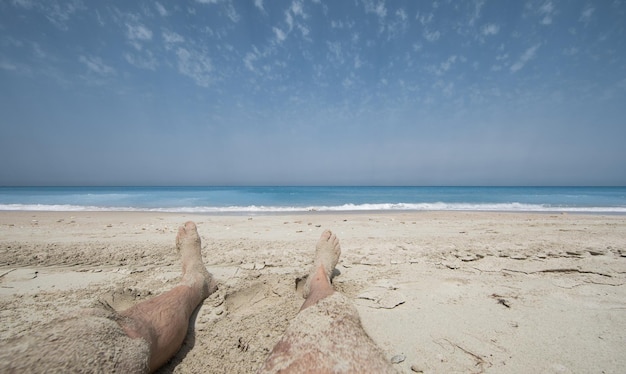 pés masculinos na praia vista mar e céu