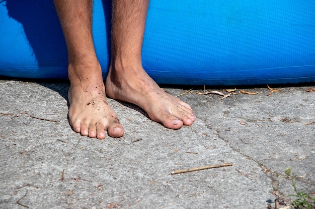 Pés masculinos sujos descalços na superfície dura do chão