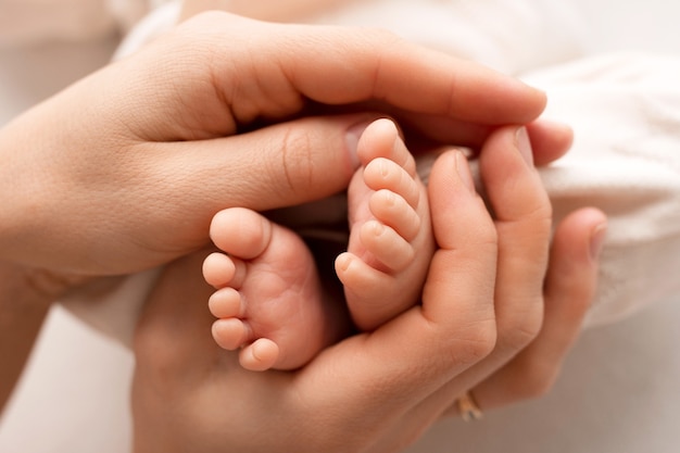 Pés minúsculos de uma criança recém-nascida nas mãos de um dos pais. bebê de uma semana. a imagem dos primeiros dias de vida. imagem do conceito de família feliz, maternidade e infância feliz. foto de alta qualidade