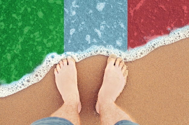 Pés na praia ensolarada com bandeira Itália vista superior no mar surf