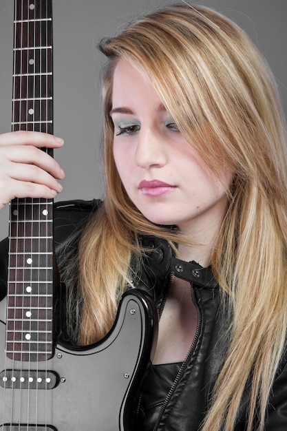 Pesada, hermosa chica rubia con guitarra eléctrica negra