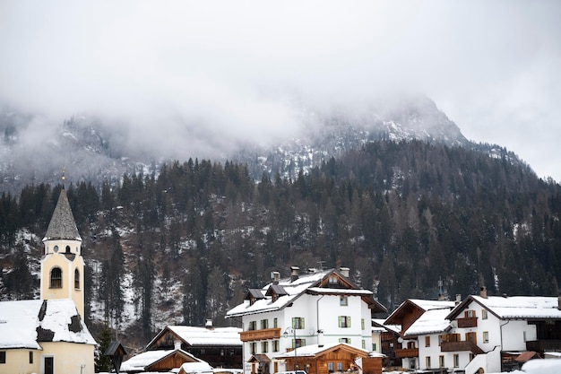 Pesadas nubes de nieve cuelgan sobre las montañas cubiertas de nieve y los abetos en el pequeño pueblo turístico de montaña