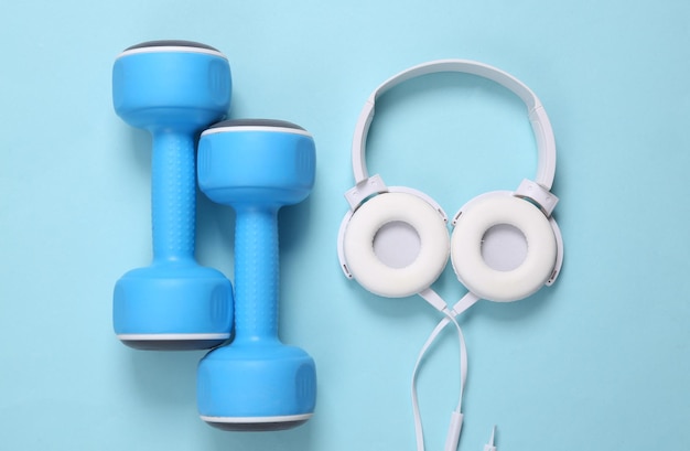 Pesas y auriculares sobre un fondo azul Accesorios de fitness Vista superior