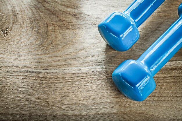 Pesas azules con mancuernas en el concepto de fitness de tablero de madera.