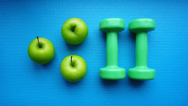 Pesas cerca de manzanas verdes sobre fondo azul. Estilo de vida saludable y concepto deportivo. Fruta de manzana y barras verdes. Régimen de salud y símbolos de fitness.