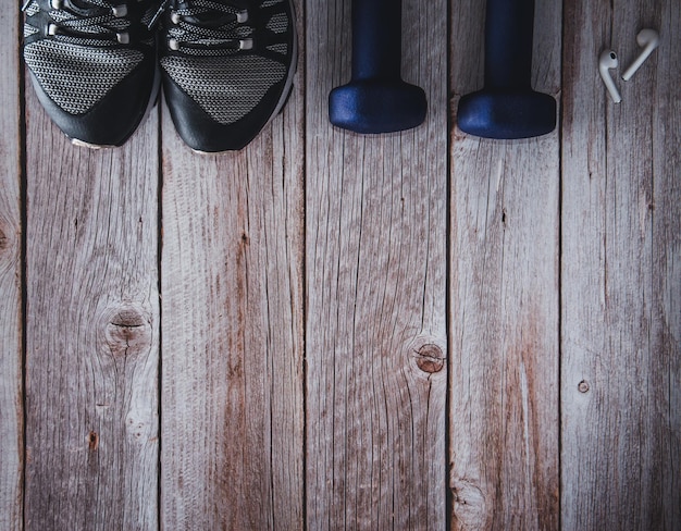 Pesas de fitness con entrenadores y auriculares sobre fondo de madera Accesorios de gimnasio Espacio de copia