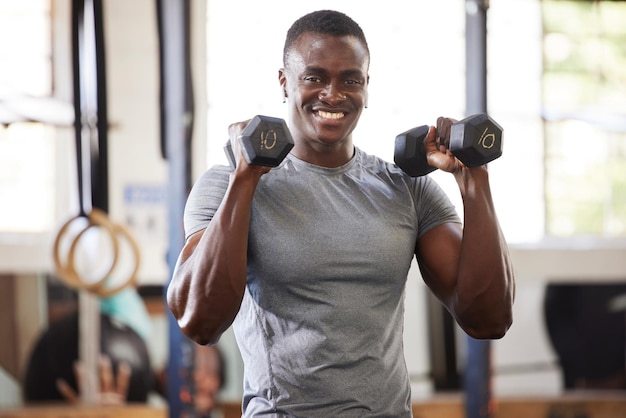 Pesas de fitness y retrato de un hombre negro levantando para entrenamiento muscular y potencia en el gimnasio Sonríe fuerte y atleta africano haciendo ejercicio o deportes para culturismo y cardio