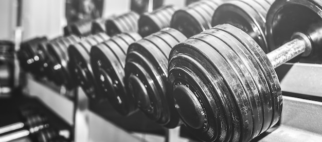 Pesas pesadas en bruto en el gimnasio. Motivación deportiva fitness. Estilo de vida saludable y feliz. Ejercicios con barras de pesas. Fotografía en blanco y negro.