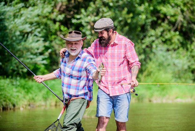 Pesca engraçada. amizade masculina. vínculo familiar. dois pescadores felizes com vara de pescar e rede. pai e filho pescando. fim de semana de verão. pescador de homens maduros. hobby e atividade esportiva. Isca para trutas.