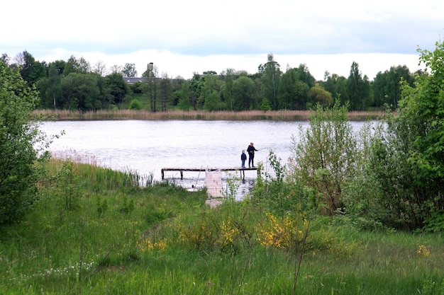 La pesca es la mejor recreación al aire libre para toda la familia un hombre y un niño se paran en un puente en medio de un lago y pescan con una caña de pescar