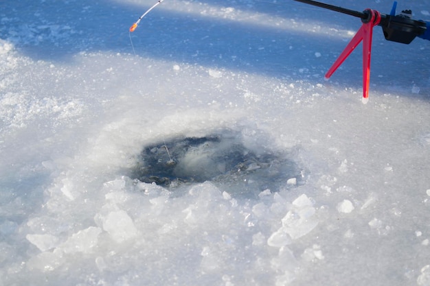 Pesca no gelo de inverno pesca no gelo no inverno pequena vara de pesca fica perto de um buraco no gelo de um ri