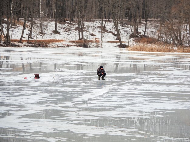 Pesca peligrosa sobre hielo primaveral húmedo. Pescador sobre hielo fundido húmedo. Rusia.