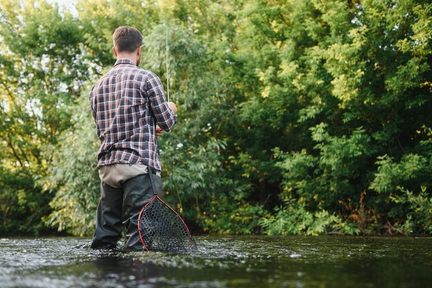 Pesca Pescador y trucha Pescador en río salvaje