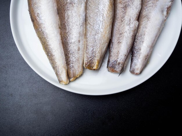 Pescada de peixe cru em prato branco peixe rico em cálcio