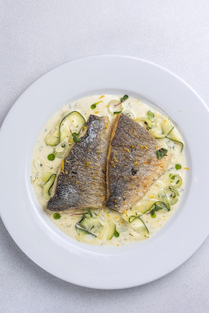 Pescado al horno con calabacín y eneldo en un plato blanco