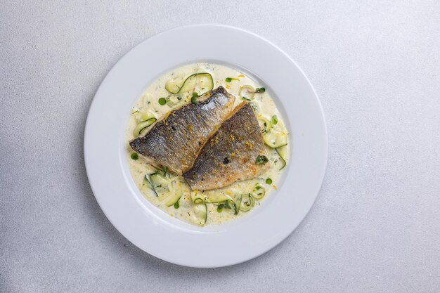 Pescado al horno con calabacín y eneldo en un plato blanco