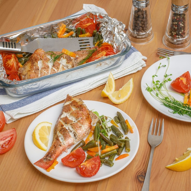 Foto pescado al horno fresco con verduras servido en plato sobre mesa de madera