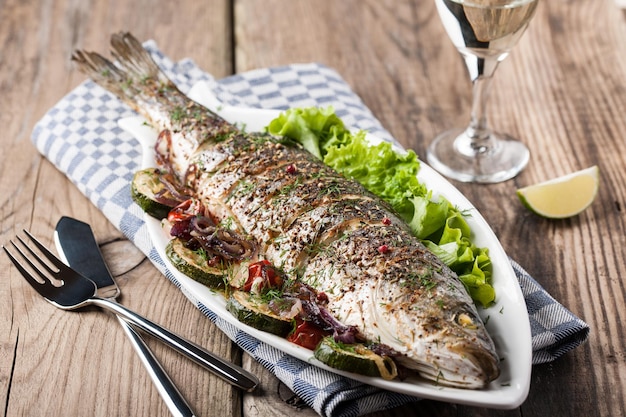 Pescado al horno con verduras y una copa de vino blanco